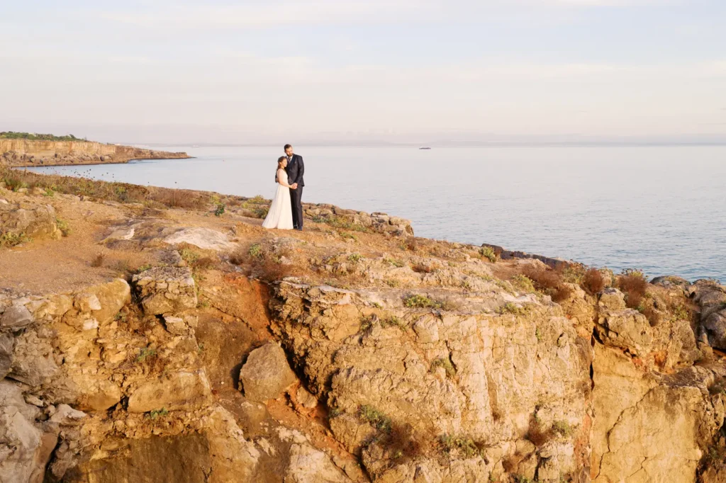Couple on their wedding day at golden hour at the cliffs of Cascais right outside of the Guia Lighthouse (farol da Guia) wit perfect sea view