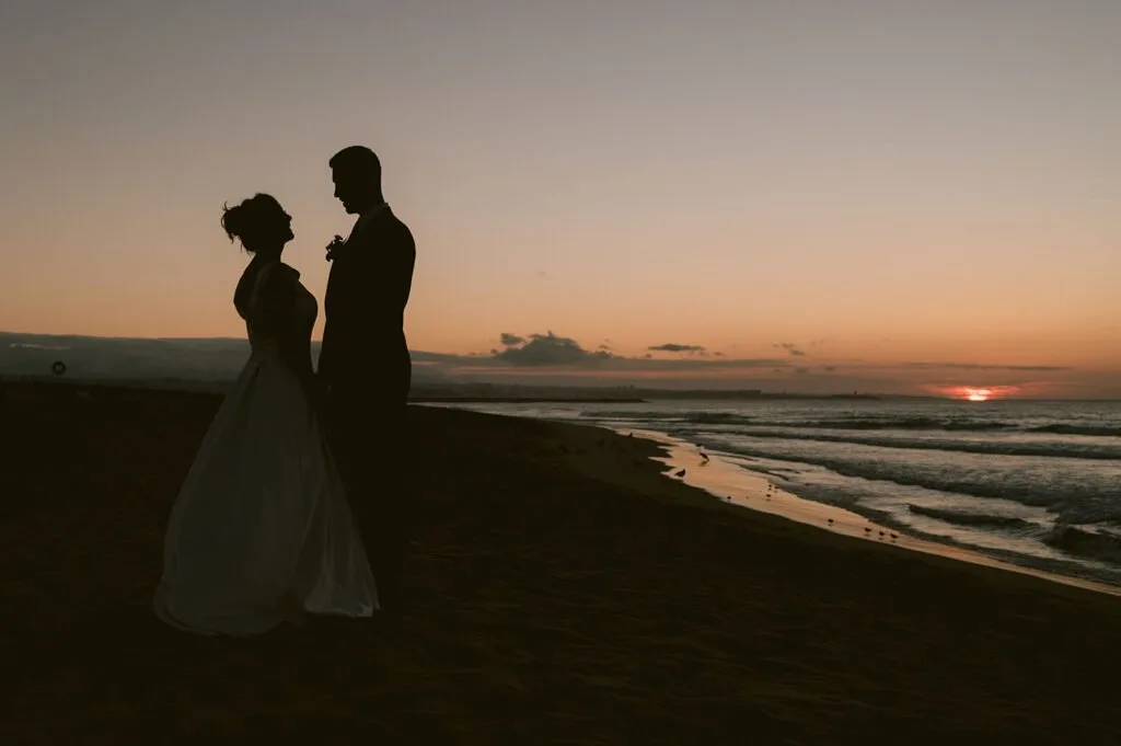 Silhueta de casal de noivos em final de dia na praia da costa da caparica. Casamento no pé nú - Beach club