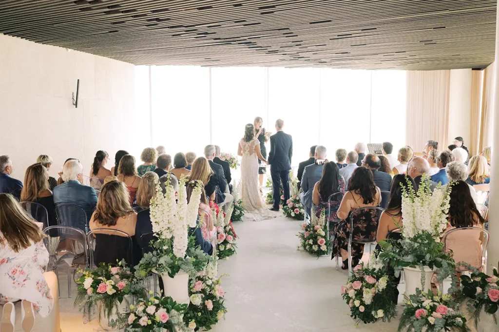 Bride and groom during a civil wedding ceremony in the glass-enclosed indoor hall of Forte Guincho Secret Spot in Cascais.