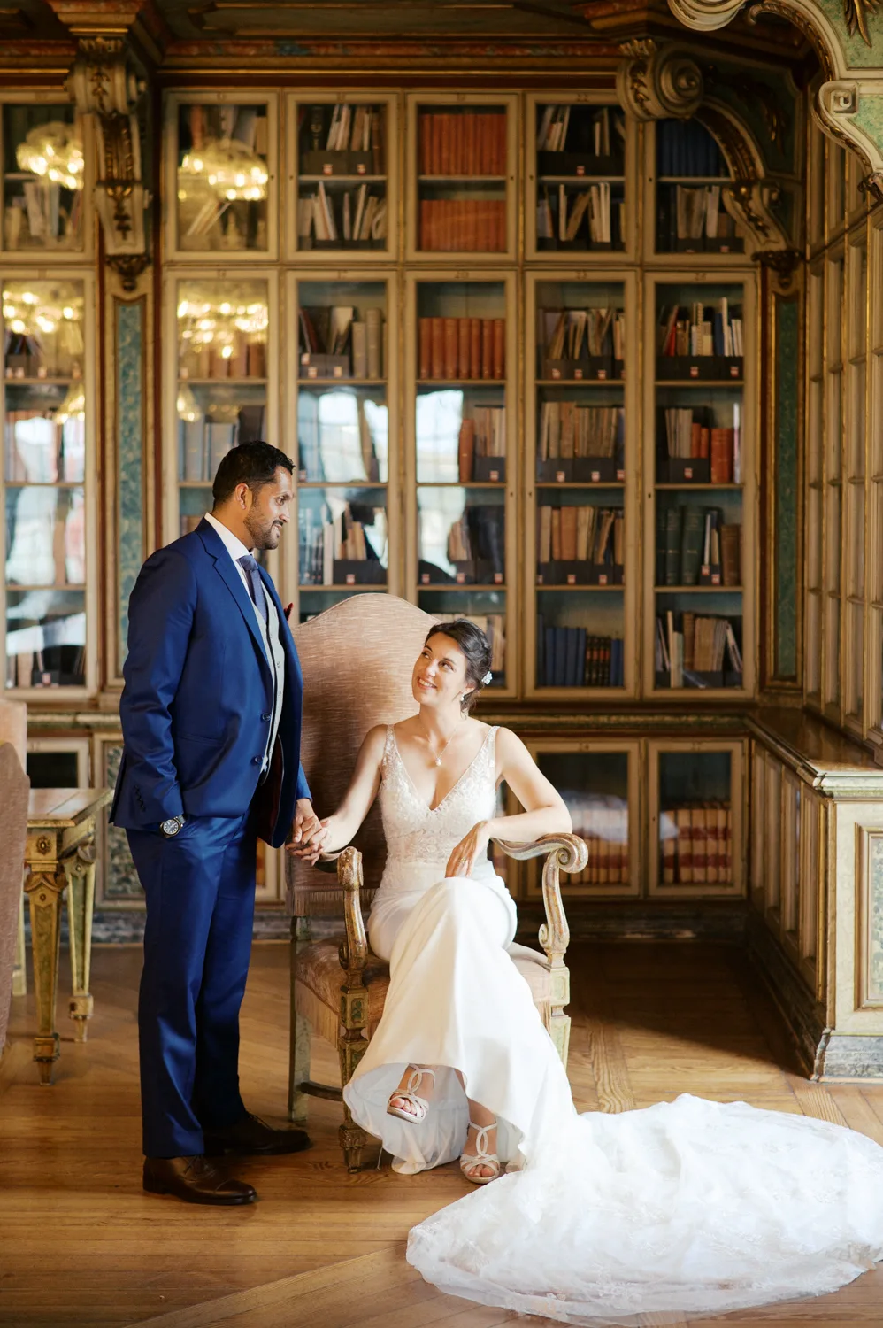 Retrato documental e elegante de noivos rodeados por livros na impressionante biblioteca do Palácio da Cruz Vermelha em Lisboa.
