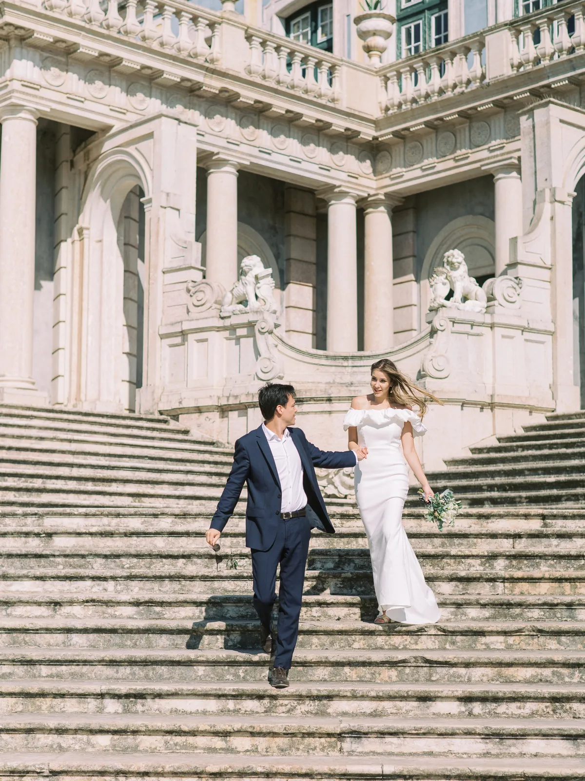 Bride and groom coming down a majestic stairs at Palácio Nacional de Queluz, Sintra, Portugal