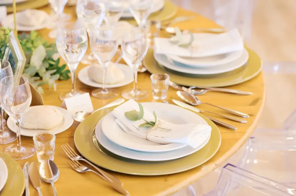 Detalhe de decoração de mesa rústico-chique na Quinta da Bichinha, com marcadores de lugar, loiça elegante e apontamentos de eucalipto em tons naturais.