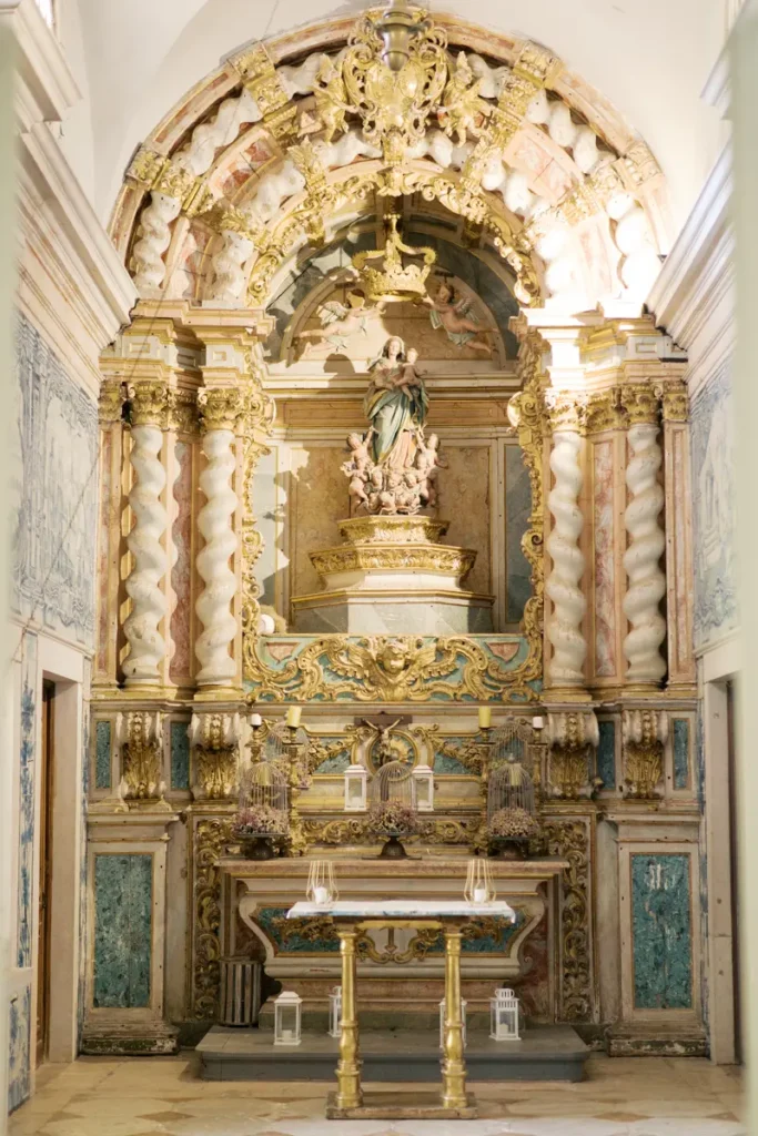 The stunning historic altar of the 18th-century chapel at Quinta do Torneiro, an authentic and ornate visual backdrop with gilded columns, a statue of the Virgin Mary, and blue and white tile panels, perfect for your destination wedding in Portugal, though not for official Catholic ceremonies.