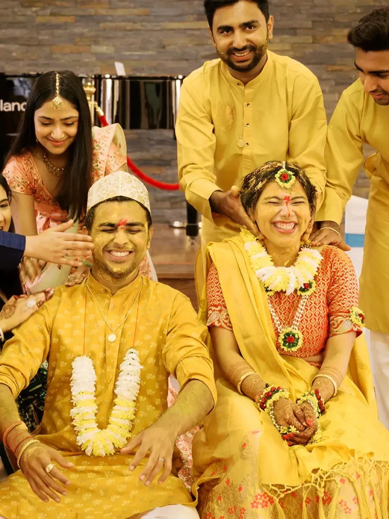 Moments of pure joy and laughter during the Pithi ritual, with the family applying the yellow turmeric paste to the couple at a Hindu wedding.