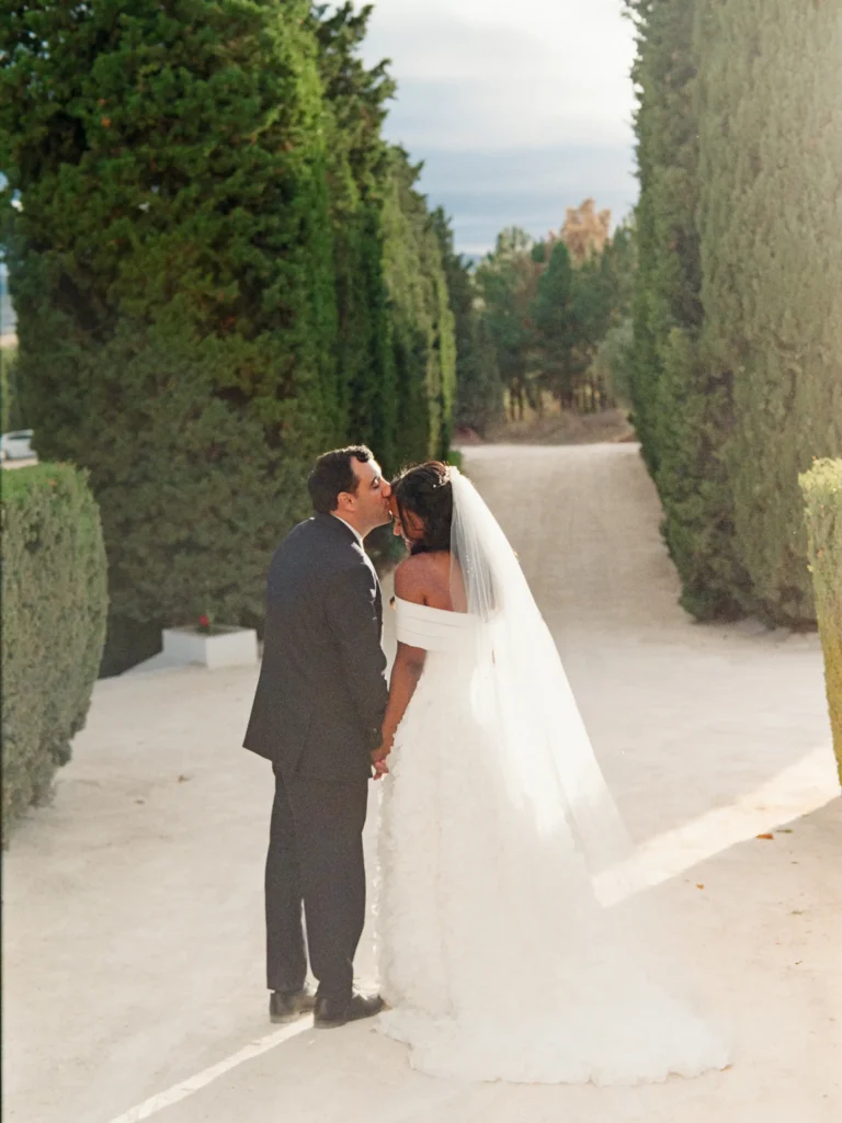 Bride and groom walking through a sun-drenched vineyard in Portugal, captured on Kodak Gold film.